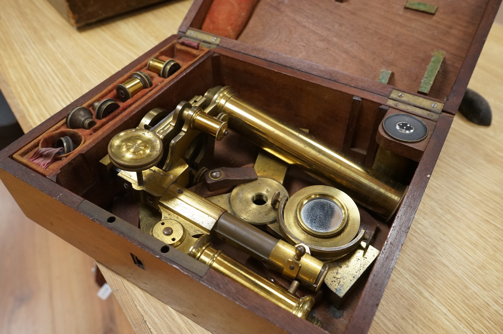 A mahogany cased 19th century brass field microscope, the body separates into sections, in a fitted case together with a selection of alternative lenses and other accessories, the microscope is unsigned, when closed the